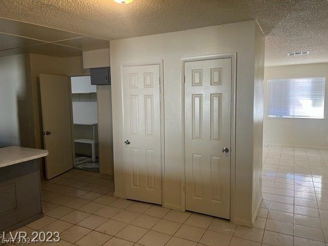 unfurnished bedroom featuring a textured ceiling and light tile floors