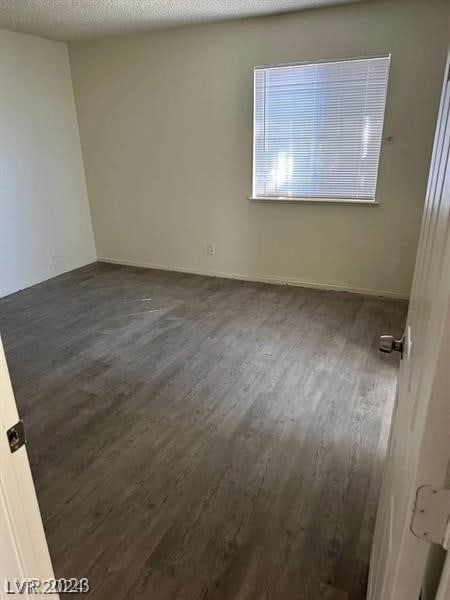 unfurnished room with a textured ceiling and dark wood-type flooring