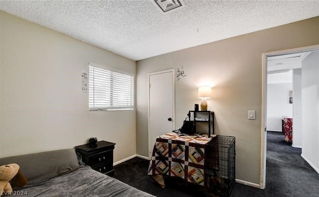 bedroom with a textured ceiling and dark colored carpet