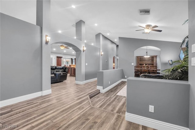 foyer featuring arched walkways, light wood-style floors, visible vents, and a ceiling fan