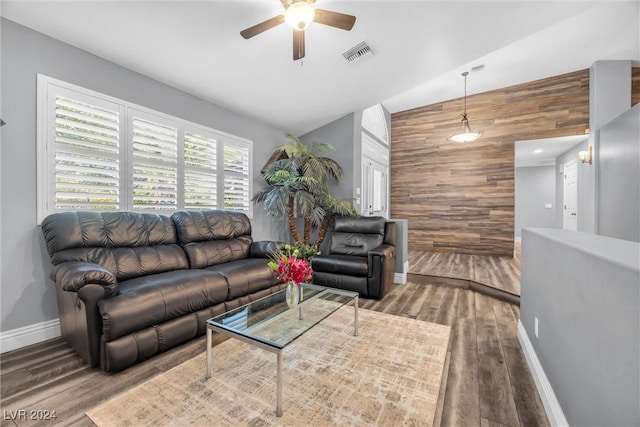 living room featuring an accent wall, visible vents, wood walls, and wood finished floors