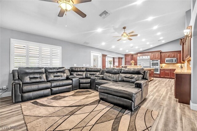 living room featuring vaulted ceiling, light hardwood / wood-style flooring, and ceiling fan