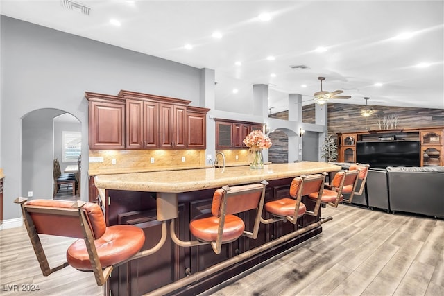 kitchen with light hardwood / wood-style floors, high vaulted ceiling, tasteful backsplash, and ceiling fan