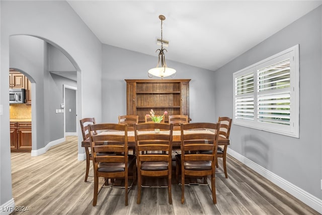 dining space featuring light wood-style flooring, arched walkways, visible vents, and lofted ceiling