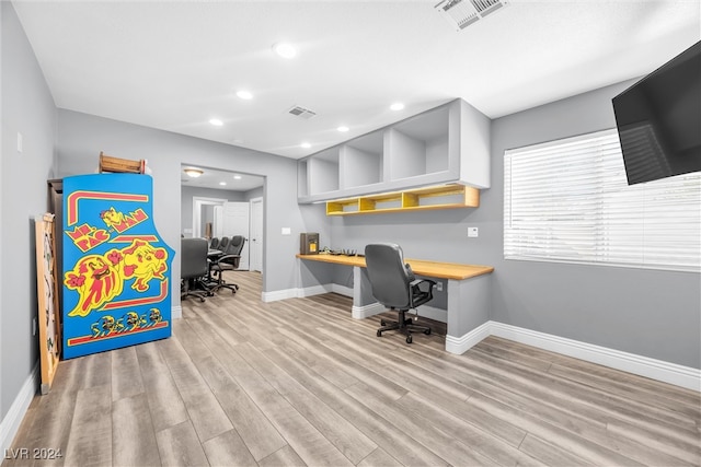 office with built in desk and light wood-type flooring