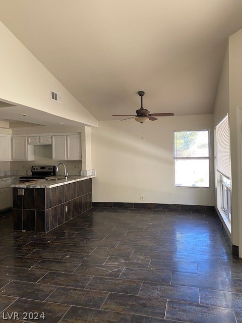 unfurnished living room featuring ceiling fan, dark hardwood / wood-style floors, sink, and high vaulted ceiling