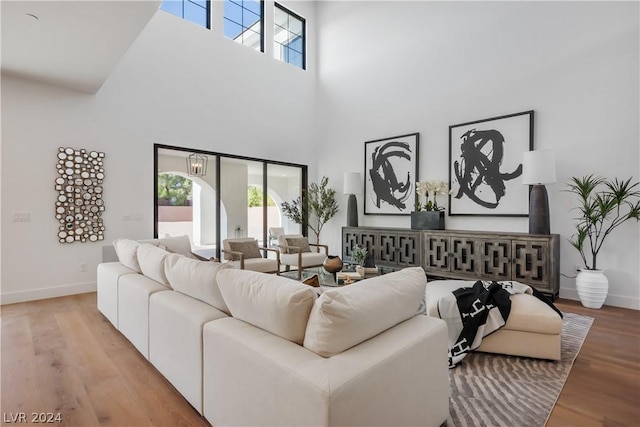 living room with a towering ceiling and light hardwood / wood-style flooring