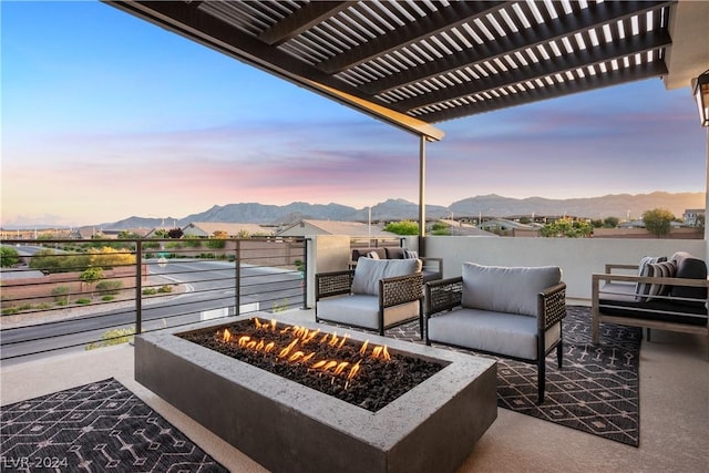 patio terrace at dusk featuring a pergola, a mountain view, and a fire pit