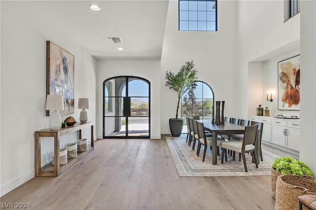 dining space featuring a high ceiling and light hardwood / wood-style flooring