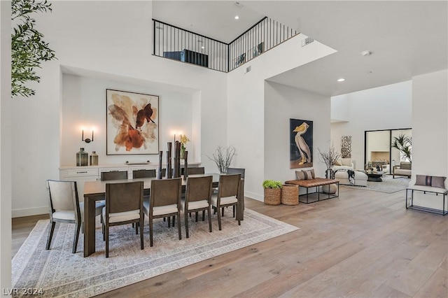 dining space with a towering ceiling and light wood-type flooring