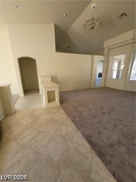 interior space with a chandelier, tile floors, and high vaulted ceiling