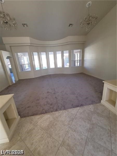 empty room featuring a chandelier, plenty of natural light, and carpet floors