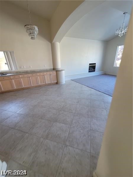 interior space with vaulted ceiling, a chandelier, and light tile floors