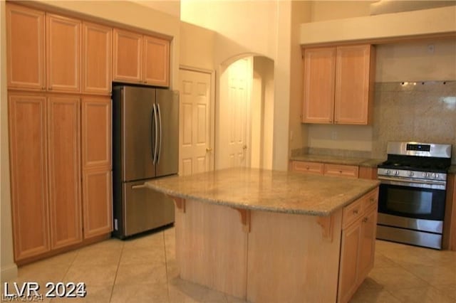 kitchen featuring appliances with stainless steel finishes, a breakfast bar area, a kitchen island, and light tile flooring