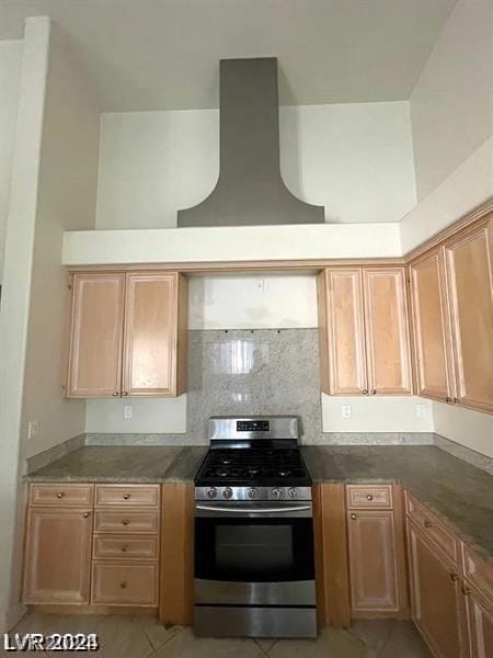 kitchen with backsplash, stainless steel range with gas stovetop, and light tile floors