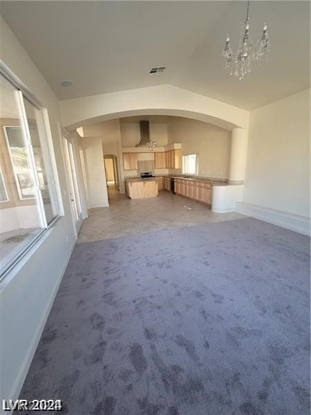 unfurnished living room with lofted ceiling, an inviting chandelier, and carpet flooring