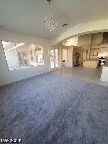 unfurnished living room with vaulted ceiling, carpet floors, and an inviting chandelier