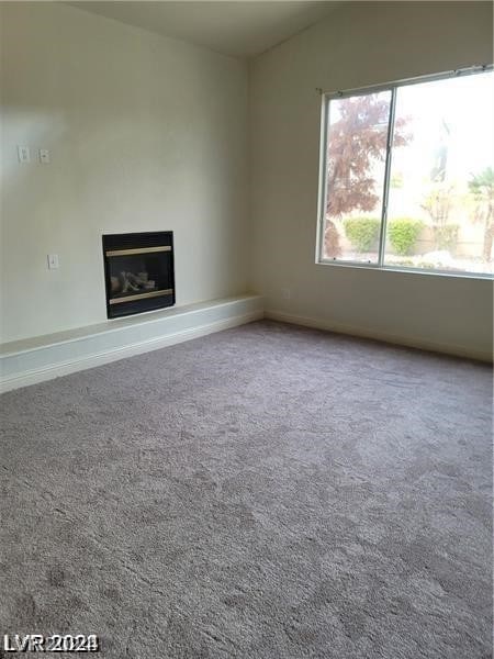 unfurnished living room with vaulted ceiling and carpet