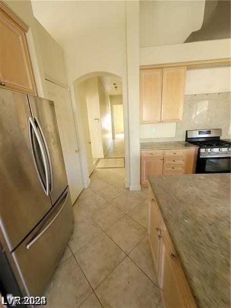 kitchen featuring light brown cabinets, stainless steel appliances, tasteful backsplash, and light tile floors