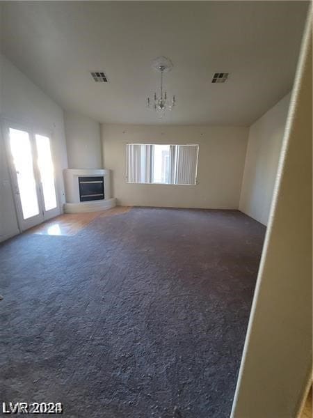 unfurnished living room featuring a notable chandelier and carpet