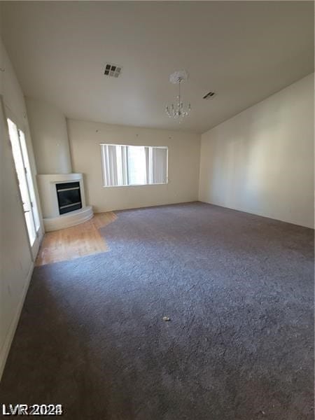 unfurnished living room with plenty of natural light, a notable chandelier, and carpet flooring