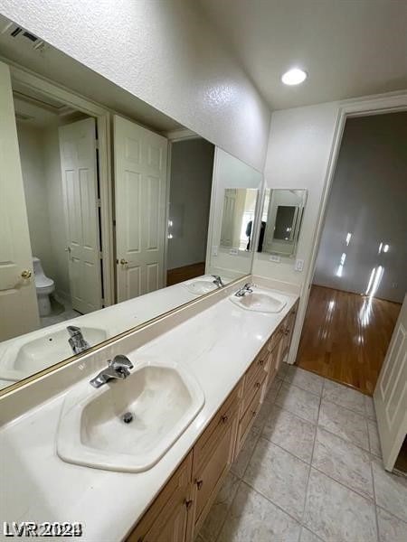 bathroom with toilet, double vanity, and tile flooring