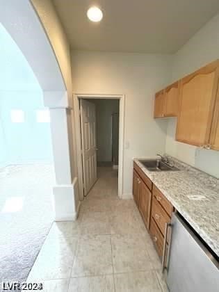 kitchen with sink, dishwasher, and light tile flooring