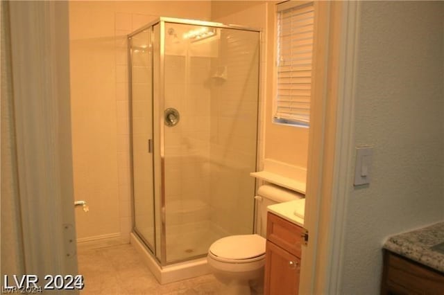 bathroom with tile floors, vanity, toilet, and a shower with shower door