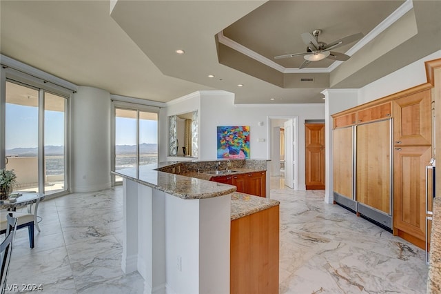 kitchen featuring light stone countertops, kitchen peninsula, ceiling fan, light tile flooring, and a raised ceiling