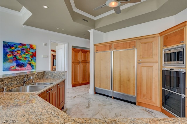 kitchen with built in appliances, a tray ceiling, light tile floors, sink, and ceiling fan