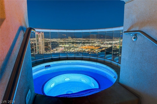 pool at night with an outdoor hot tub