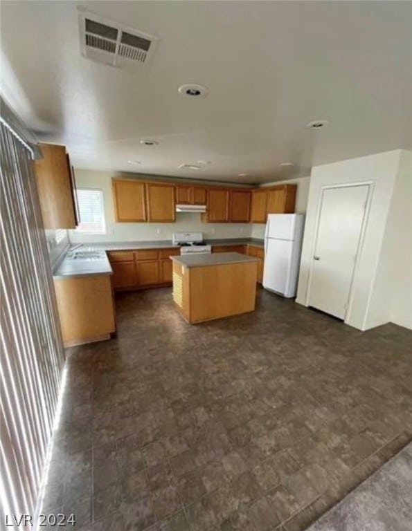 kitchen featuring a kitchen island, range, white refrigerator, and dark tile floors