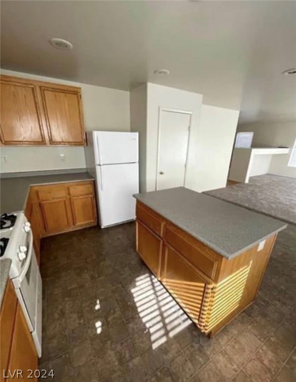 kitchen with white appliances, a kitchen island, and dark tile flooring