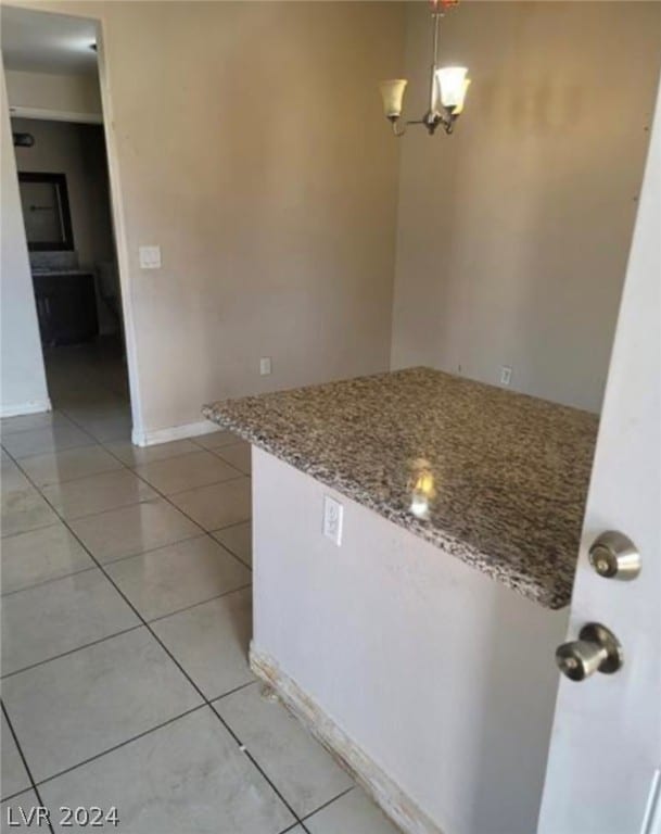 kitchen with stone countertops, light tile floors, pendant lighting, and an inviting chandelier