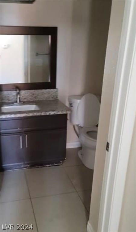 bathroom featuring tile floors, vanity with extensive cabinet space, and toilet