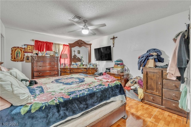 bedroom featuring ceiling fan, hardwood / wood-style floors, and a textured ceiling