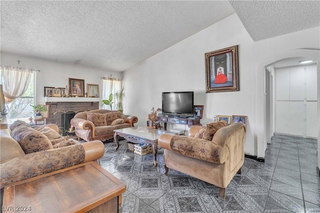 living room with dark tile patterned floors, a textured ceiling, and a brick fireplace