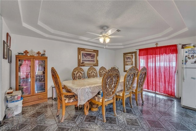 dining space featuring a textured ceiling, a tray ceiling, and ceiling fan