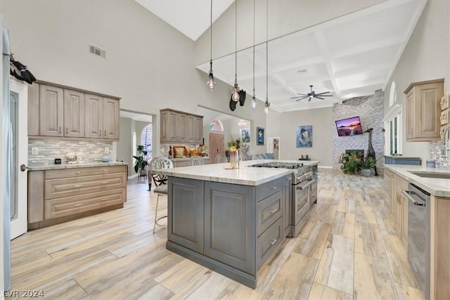 kitchen with appliances with stainless steel finishes, decorative light fixtures, a kitchen island with sink, ceiling fan, and coffered ceiling