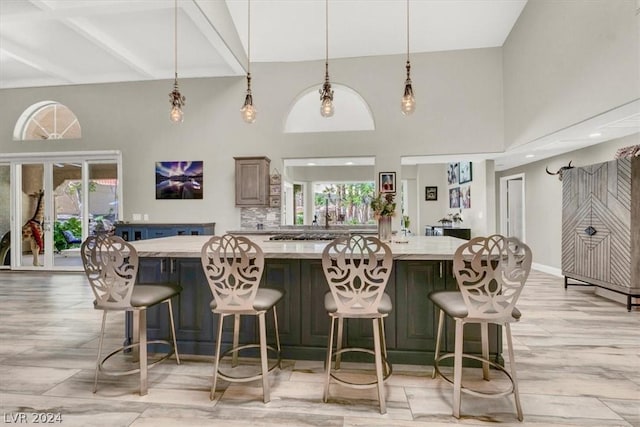 kitchen with tasteful backsplash, a spacious island, hanging light fixtures, light stone countertops, and a kitchen breakfast bar