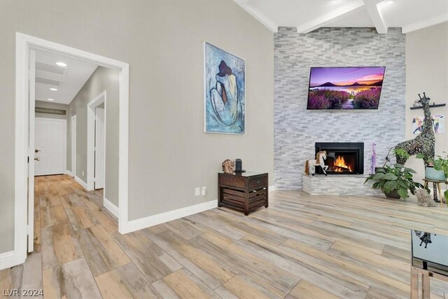 living room with light hardwood / wood-style flooring, beamed ceiling, and a fireplace