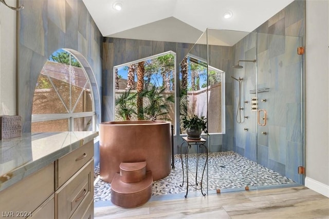 bathroom with vaulted ceiling, a shower with shower door, and vanity