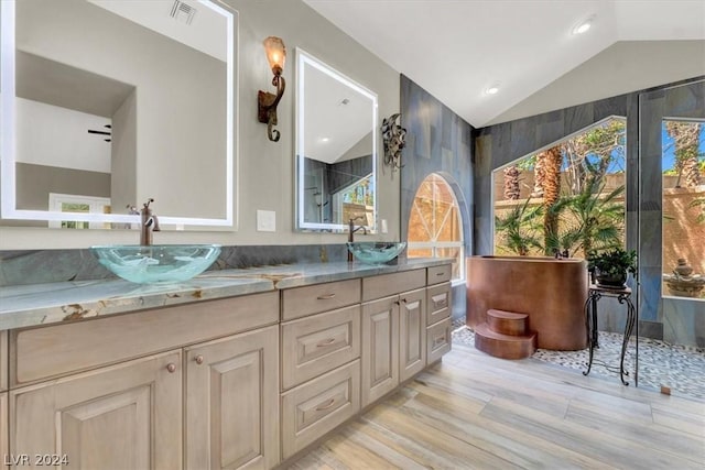 bathroom featuring a wealth of natural light, lofted ceiling, hardwood / wood-style floors, and vanity