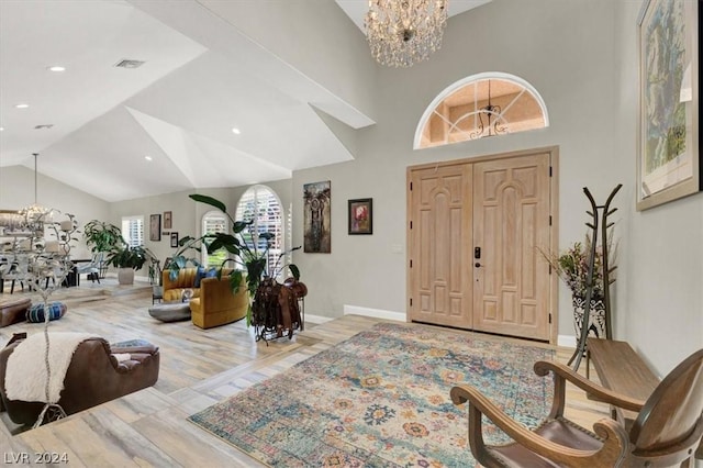 entryway featuring a chandelier, lofted ceiling, and light hardwood / wood-style floors