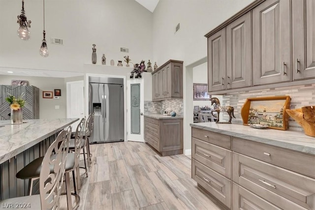 kitchen with pendant lighting, built in fridge, tasteful backsplash, and light stone countertops