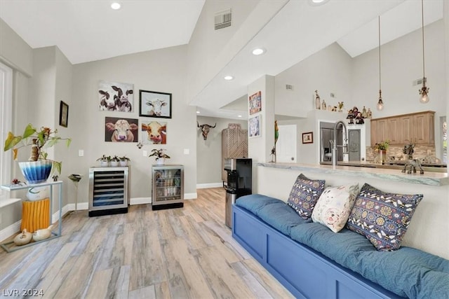 living room featuring high vaulted ceiling, light wood-type flooring, and beverage cooler