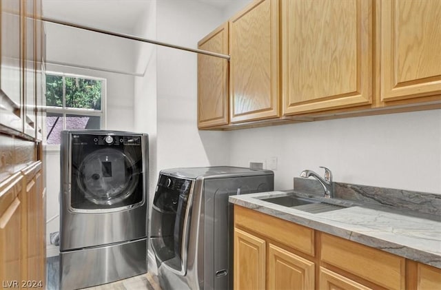 washroom with sink, washing machine and clothes dryer, and cabinets