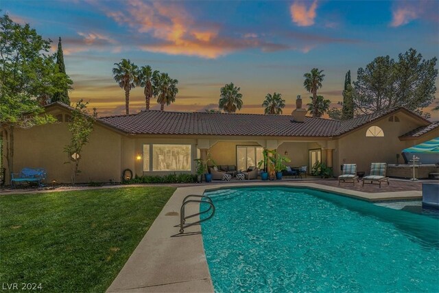 pool at dusk with a yard and a patio