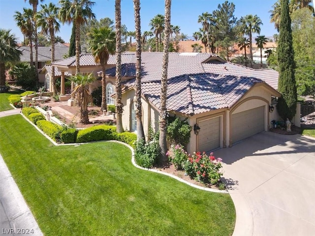 mediterranean / spanish home featuring a front lawn and a garage