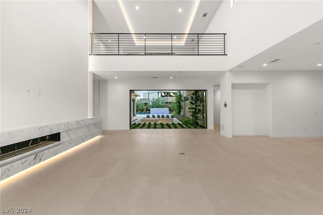 unfurnished living room featuring a fireplace and a high ceiling